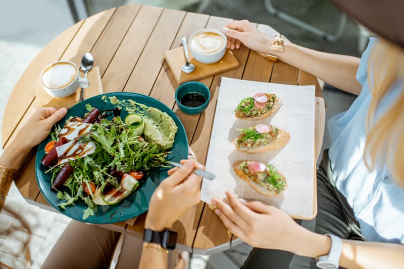 Frauen essen gesundes vegetarisches Essen im Café, Nahaufnahme von oben auf dem Tisch