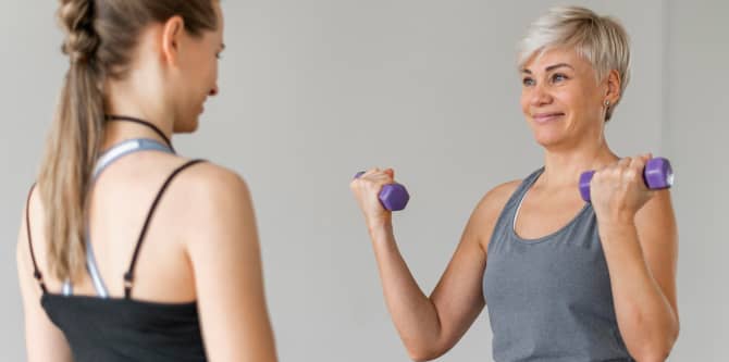Workout mit Personal Trainer mit violetten Hanteln