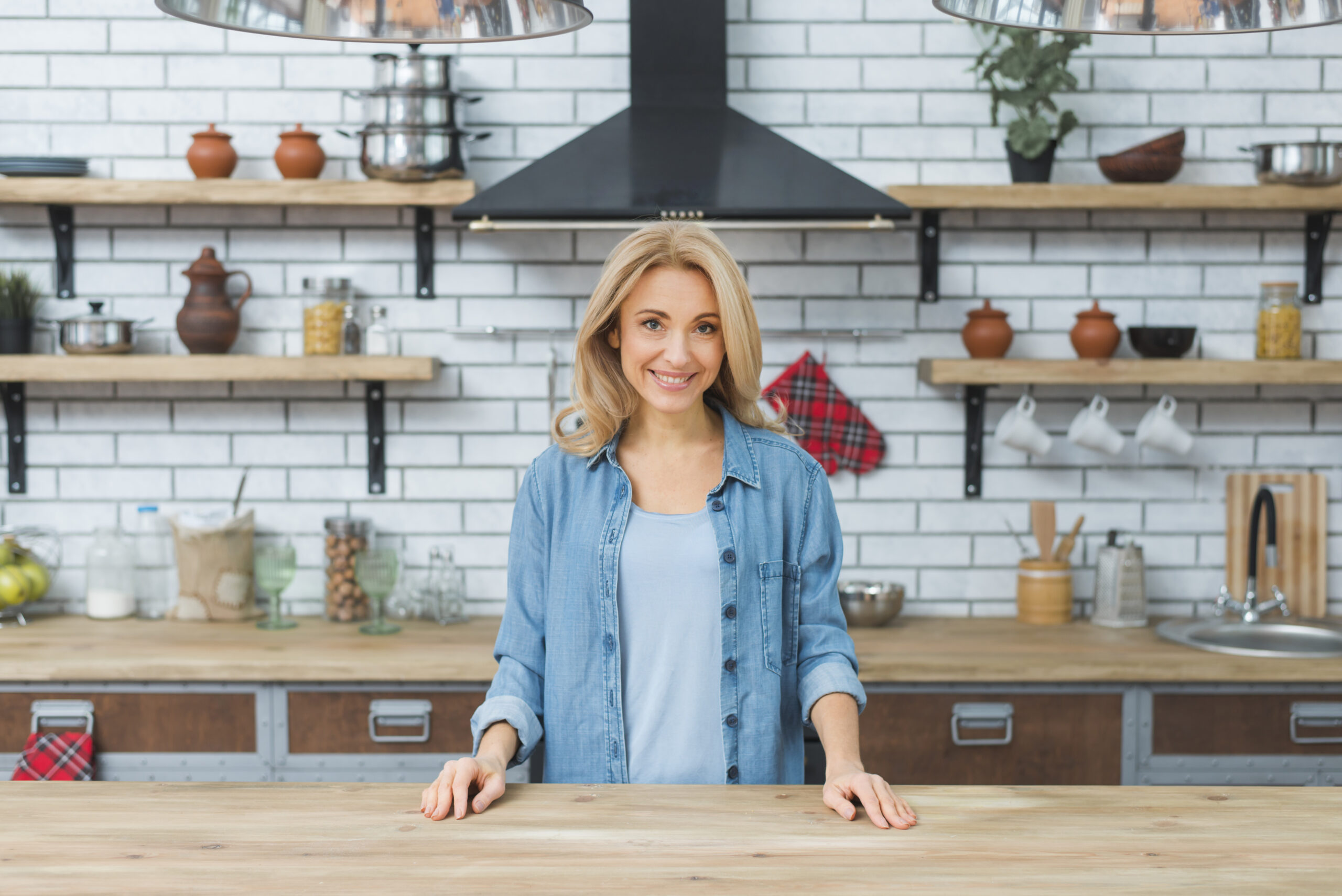 Lächelnde junge Frau, die an einem Holztisch in der Küche steht